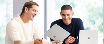 Two men holding a tab and smiling.