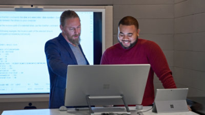 Two persons are looking at the desktop screen