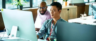 Two persons in office looking at computer screen.
