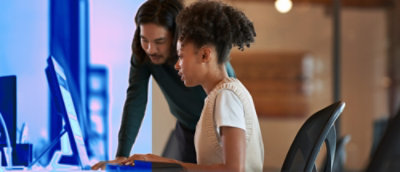 A man and a woman looking at the screen and discussing