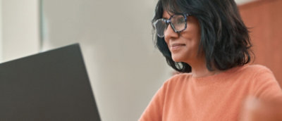  A person sitting at a desk and working on a laptop in an indoor setting.