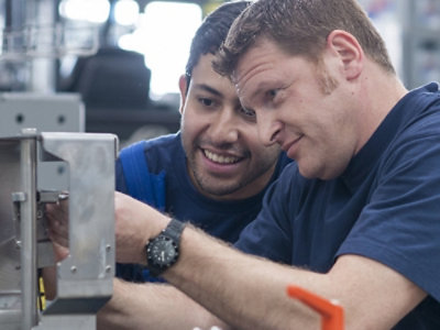 Een close-up van twee personen die naar een metalen object kijken.