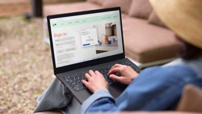Person using a laptop outdoors, viewing a sign-in page with an authentication pop-up.