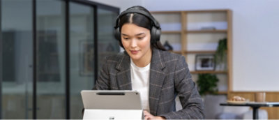 A person wearing headphones and looking at a tablet.
