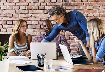A group of people looking at a laptop.