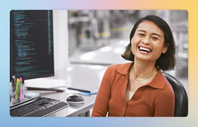 A woman laughing while looking at a computer screen.