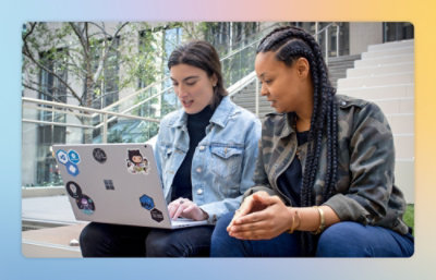 Women sitting on stairs looking at a laptop.
