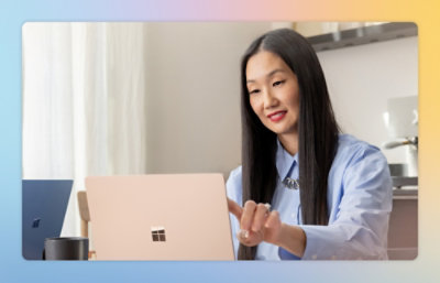 A person pointing at a laptop while wearing a blue shirt.
