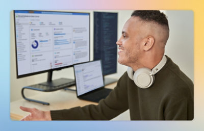A person wearing headphones working at a desk with two computer screens.
