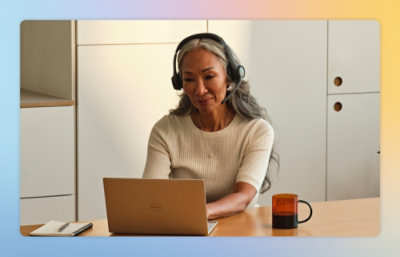 A woman wearing headphones and looking at a laptop.