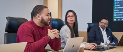 A man and woman sitting at a table with laptops.
