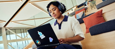 A woman wearing headphones and looking at a laptop.