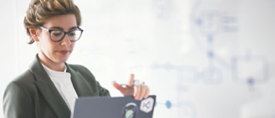 A person holding a laptop while wearing a white shirt and black jacket.