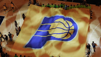 A group of people standing in a crowd holding a large flag.