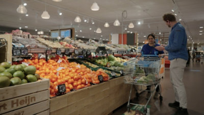 A grocery store with fruits and vegetables and wooden crates filled with produce.