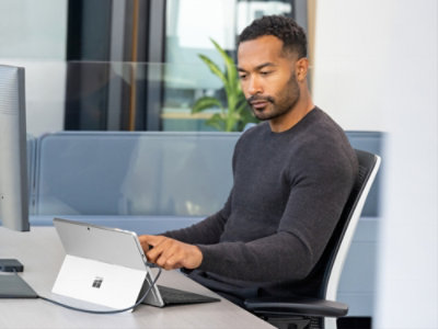 A man sitting at a desk using a tablet.