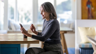A woman sitting at a table looking at her phone.