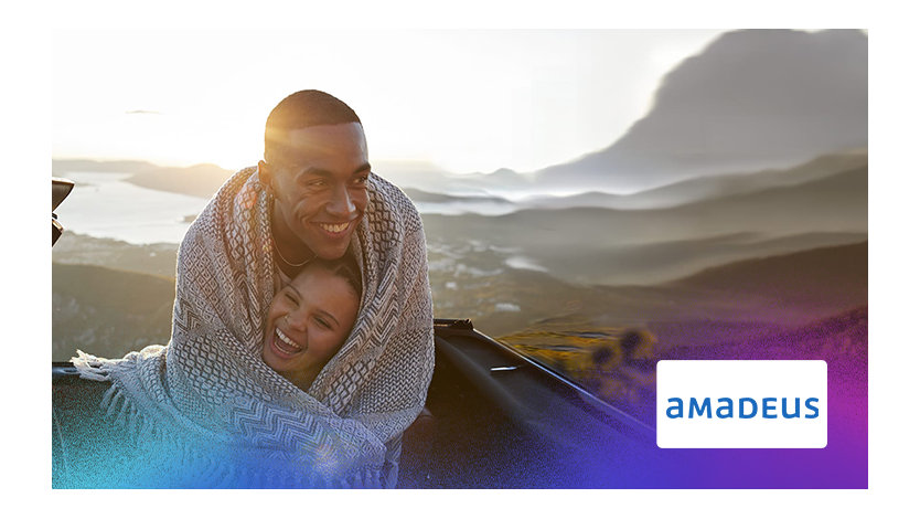 Un homme et une femme assis à l'arrière d'une voiture, discutant et souriant l'un à l'autre.