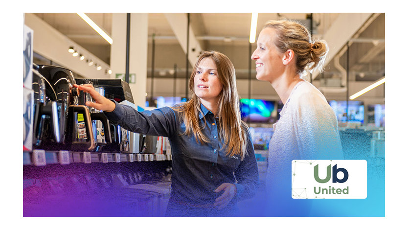 Deux femmes examinent des appareils électroniques dans un magasin, discutant des options disponibles.