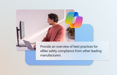 Un hombre con camisa roja mira la pantalla de un ordenador con un texto sobre el cumplimiento de las normas de seguridad para bicicletas eléctricas.