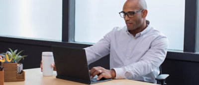Un hombre sentado frente a un escritorio usa un portátil.