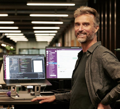 A man standing with his hands on his hips in front of a computer.