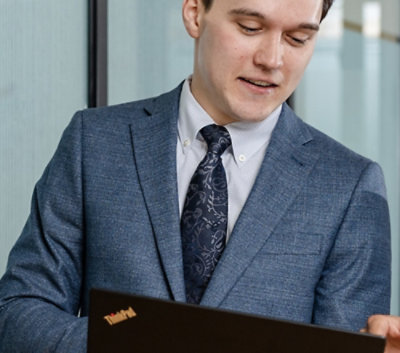 一位穿着职业装的男士看着笔记本电脑。