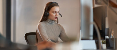 一位戴着耳机的女士看着电脑。