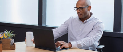 一名男子坐在办公桌前使用笔记本电脑。