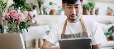 一位系着围裙的男子正在看着平板电脑。