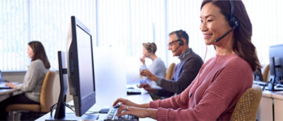 一位女士戴着耳机坐在计算机前。