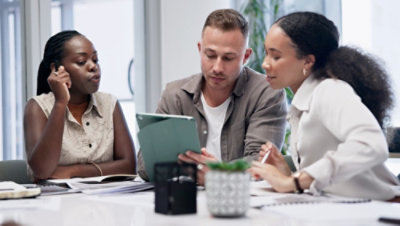 Three colleagues in discussion around a table.