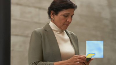 Person standing and using a smartphone indoors.