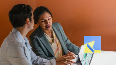 Two people reviewing content together on a tablet at a table.