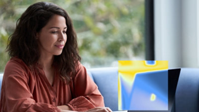 Person using a laptop while seated indoors near a window.