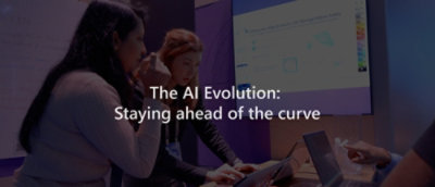A group of people looking at a laptop with text on the screen that reads The AI Evolution: Staying ahead of the curve.