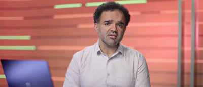 A man in a white shirt is shown against a blue and white background.
