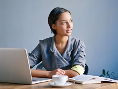 A woman looking away while sitting in front of laptop