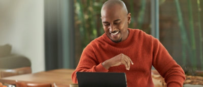 A man looking in the laptop and smiling