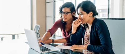 Two people looking at the laptop and discussing