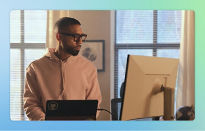 En man i rosa tröja tittar på en datorskärm.