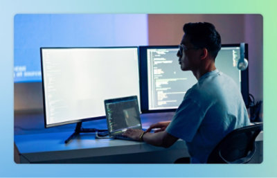 En person sitter vid ett skrivbord med en datorskärm som visar text.