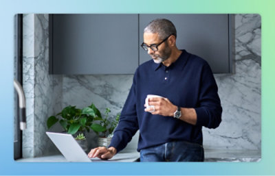 En man håller en kopp och använder en bärbar dator.