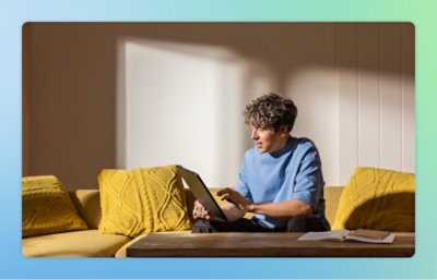 En person sitter på en soffa och använder en bärbar dator.