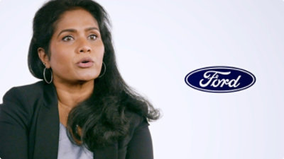 A close-up of a person's dark hair and neck wearing hoop earrings, with visible text reading Ford.