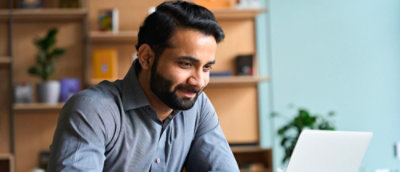 A man wearing a grey short working on his laptop
