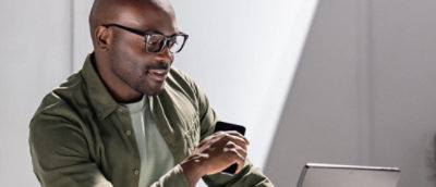A person wearing glasses and a green shirt looking at a laptop.