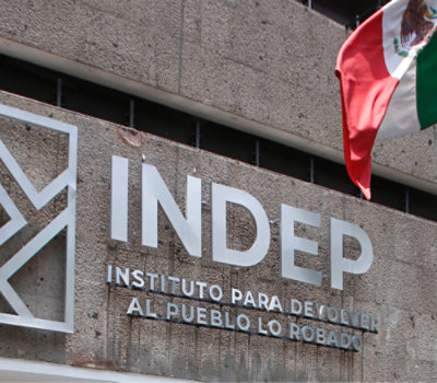 Signage of "INDEP - Instituto para Devolver al Pueblo lo Robado" on a building facade with a Mexican flag to the right.