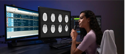 Une femme vêtue d’une chemise violette regarde un écran d’ordinateur.