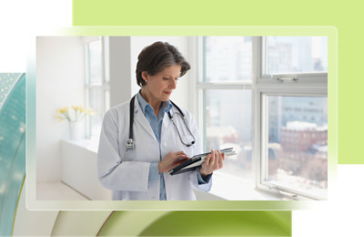Une femme en blouse blanche regardant un écran d’ordinateur.